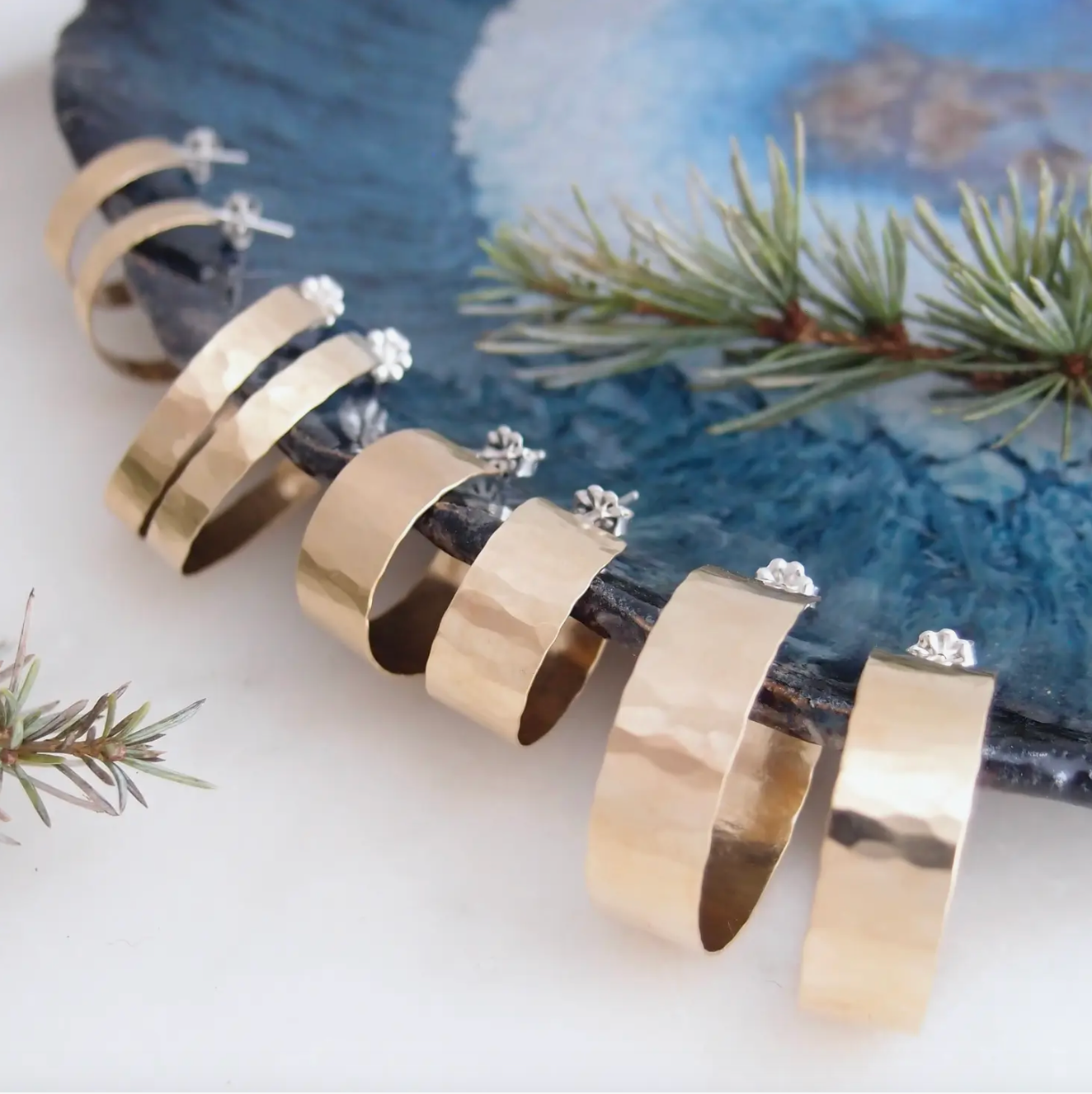 Display of 4 different types of hammered gold hoop earrings.