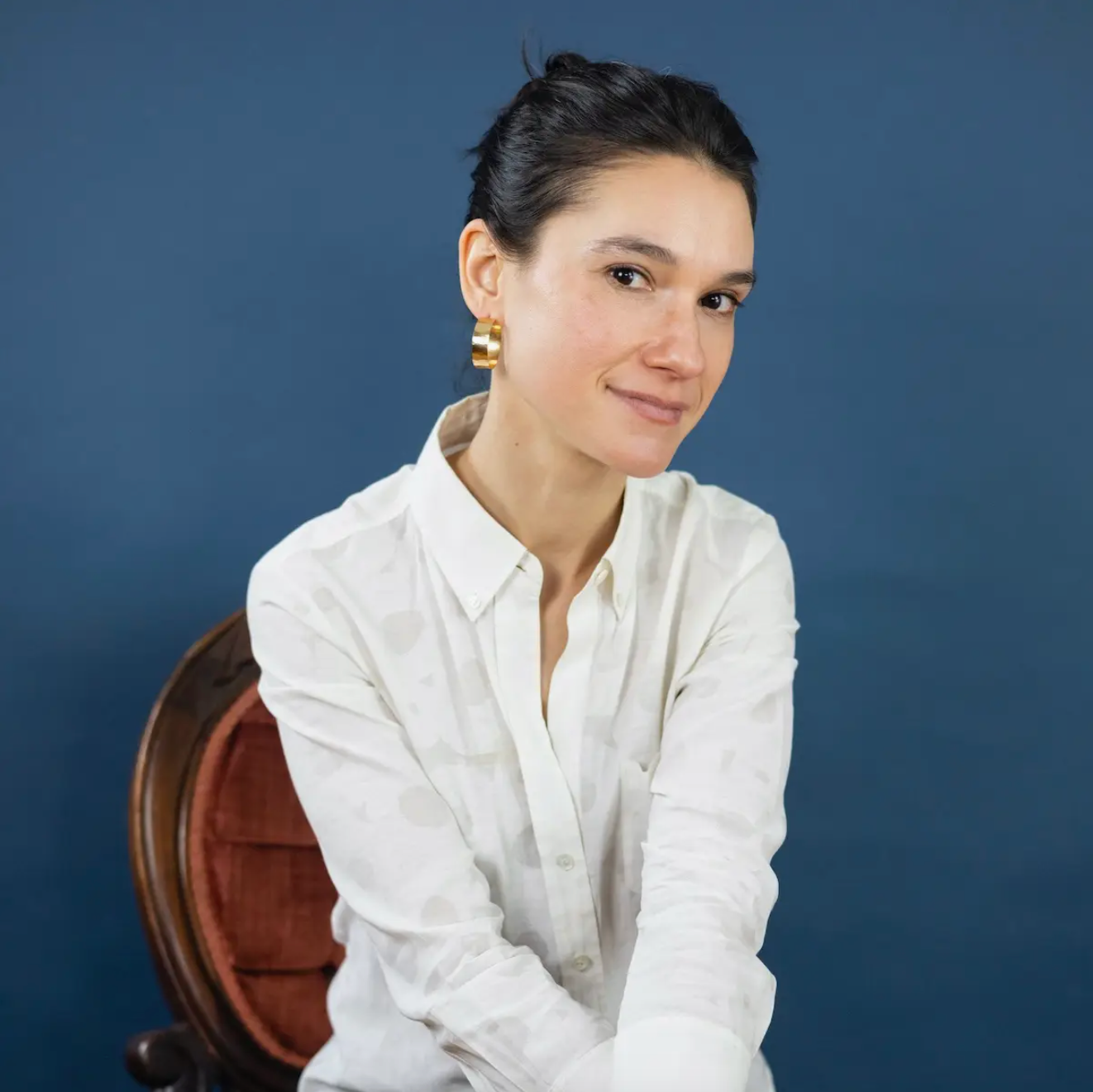 Woman wearing large, flat hammered gold hoop earrings.