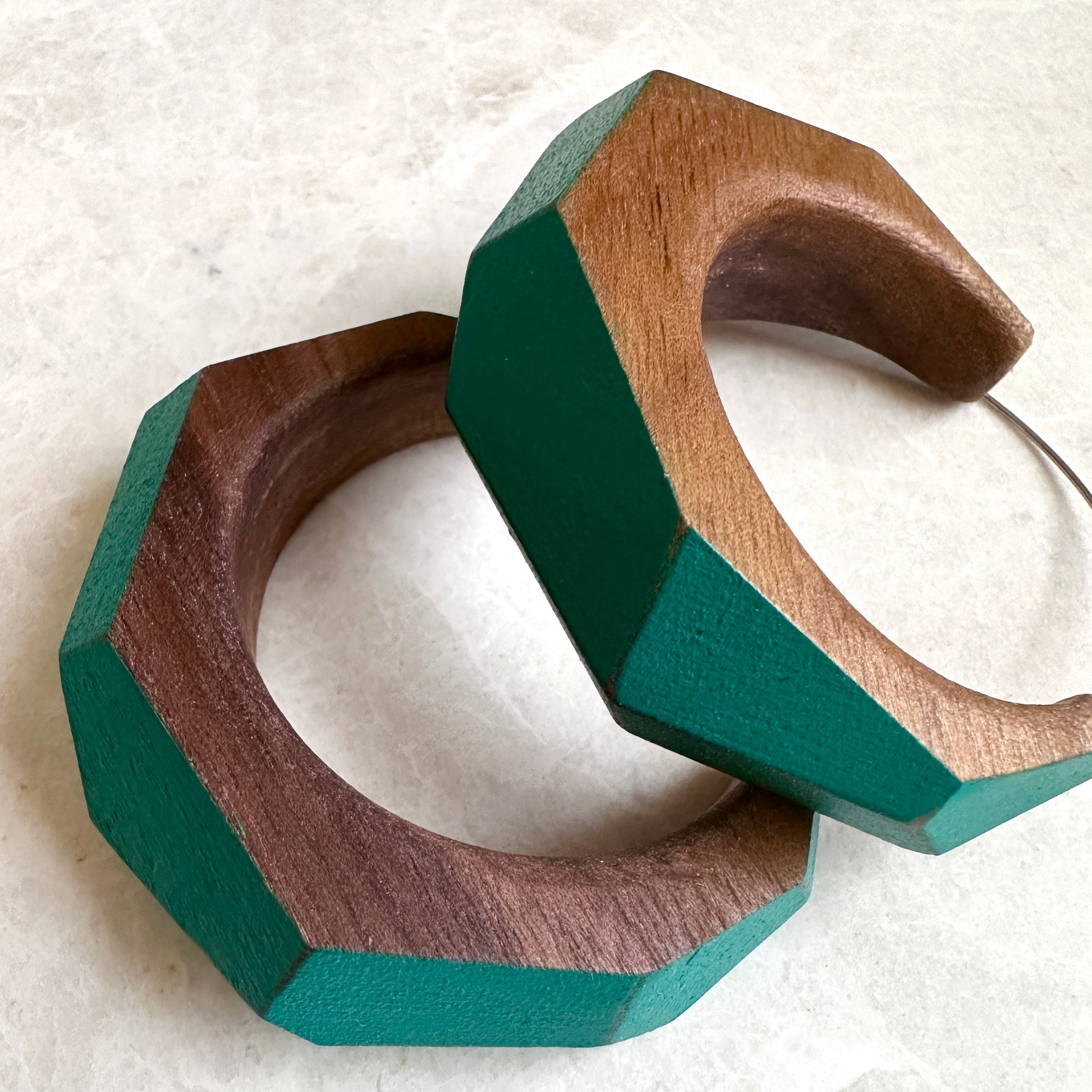 Large statement hoop earrings made from wood with turquoise painted accents, close up.