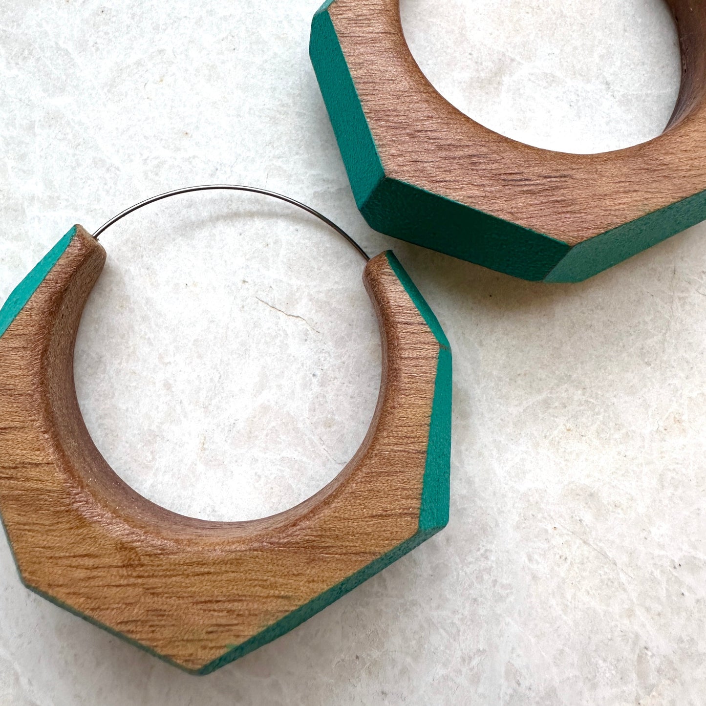 Large statement hoop earrings made from wood with turquoise painted accents, side view.
