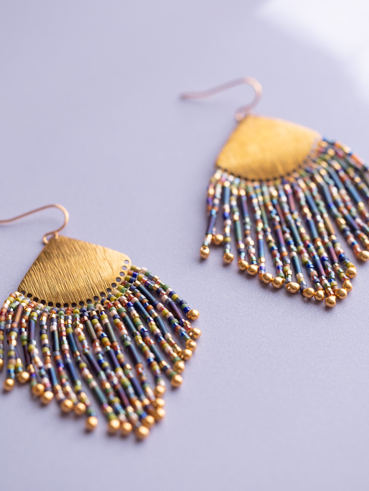 Gold beaded fringe earrings with multi colored beads, up close.