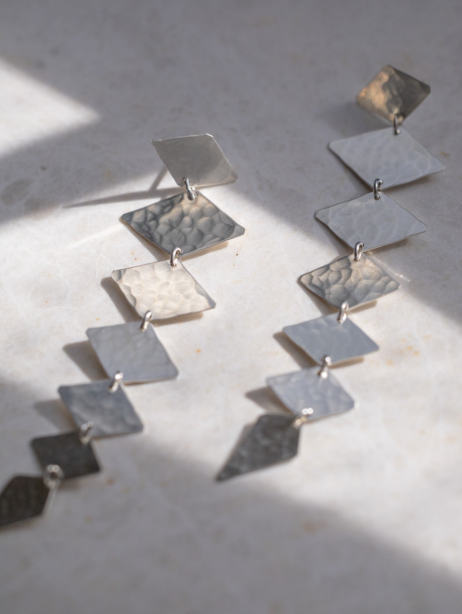 Long sterling silver earrings made from connecting diamond shapes.