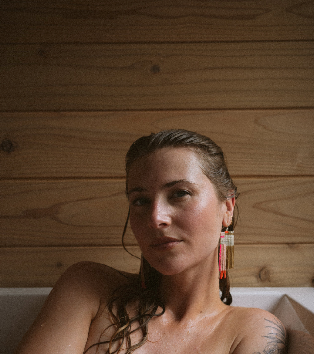 Woman wearing white, pink, orange, brown hand beaded earrings, front view.