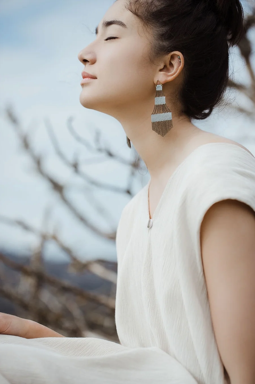 Woman wearing large light blue chandelier shaped beaded earrings.