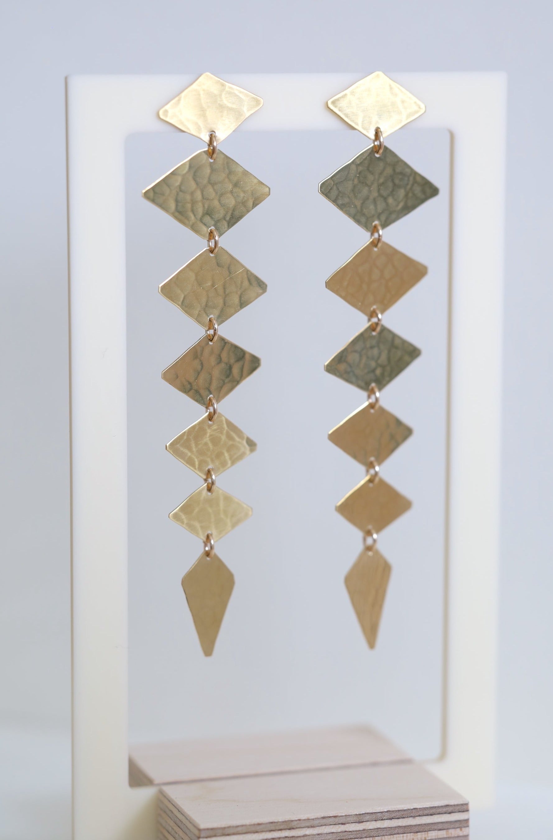 Long gold earrings made from diamond shapes that hang straight down.