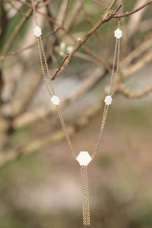 Gold hand beaded necklace in an outside setting.