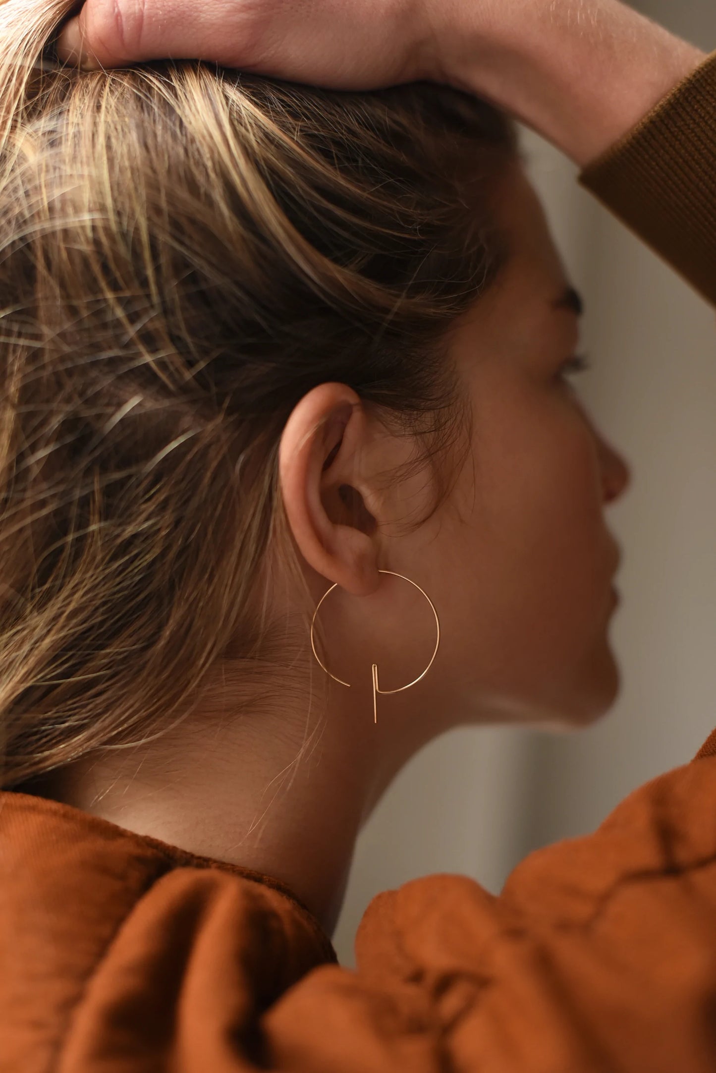 Woman wearing modern hoop threader earrings.