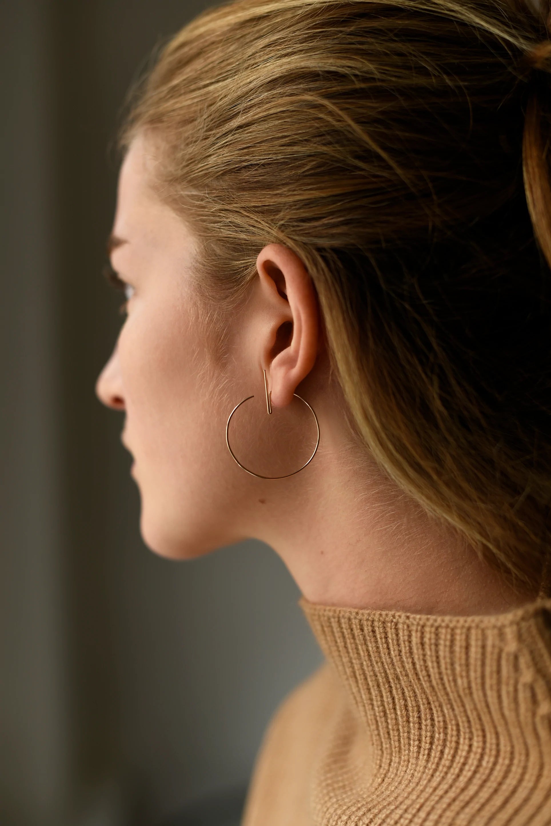 Woman wearing modern hoop threader earrings, side view.