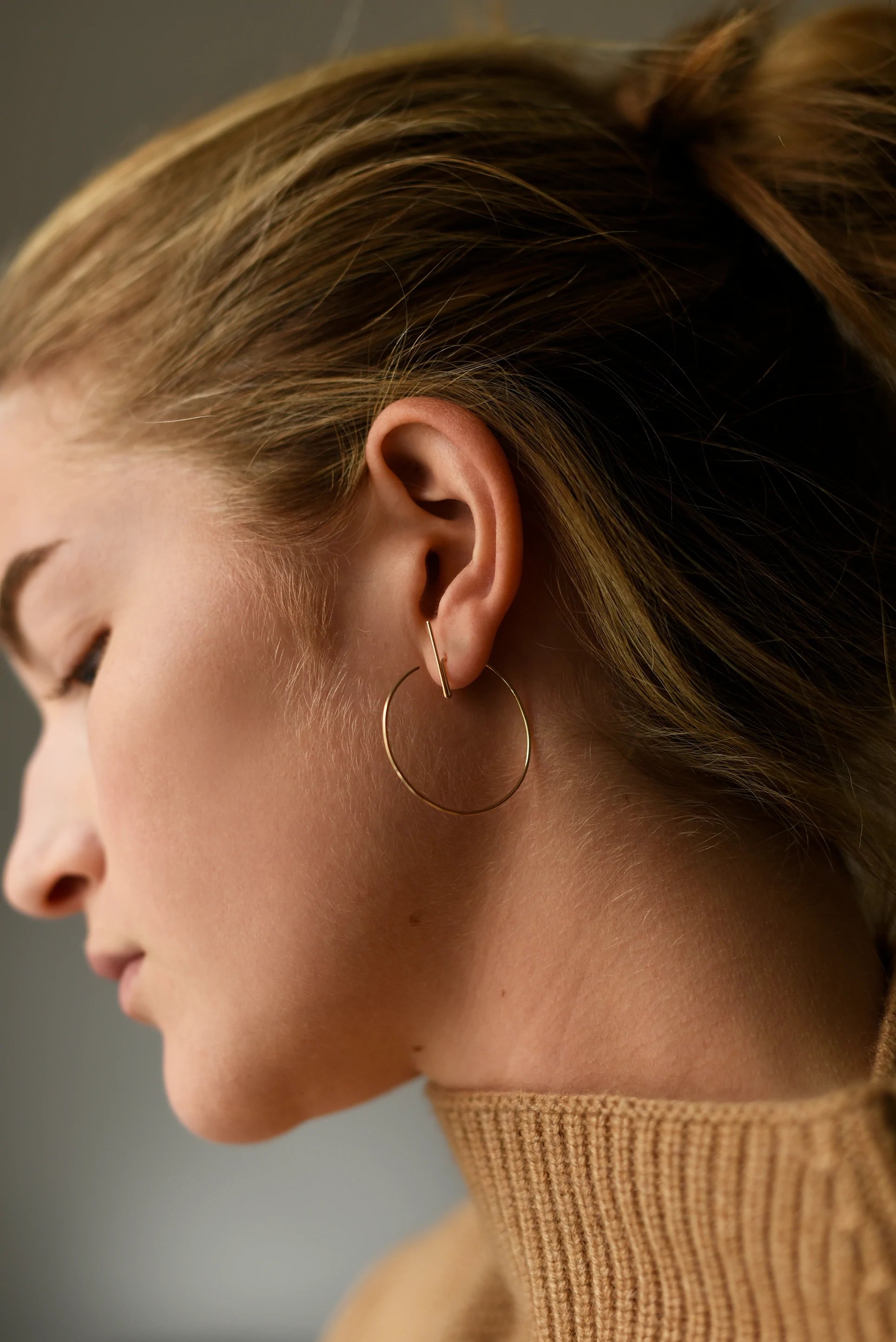 Woman wearing modern hoop threader earrings.