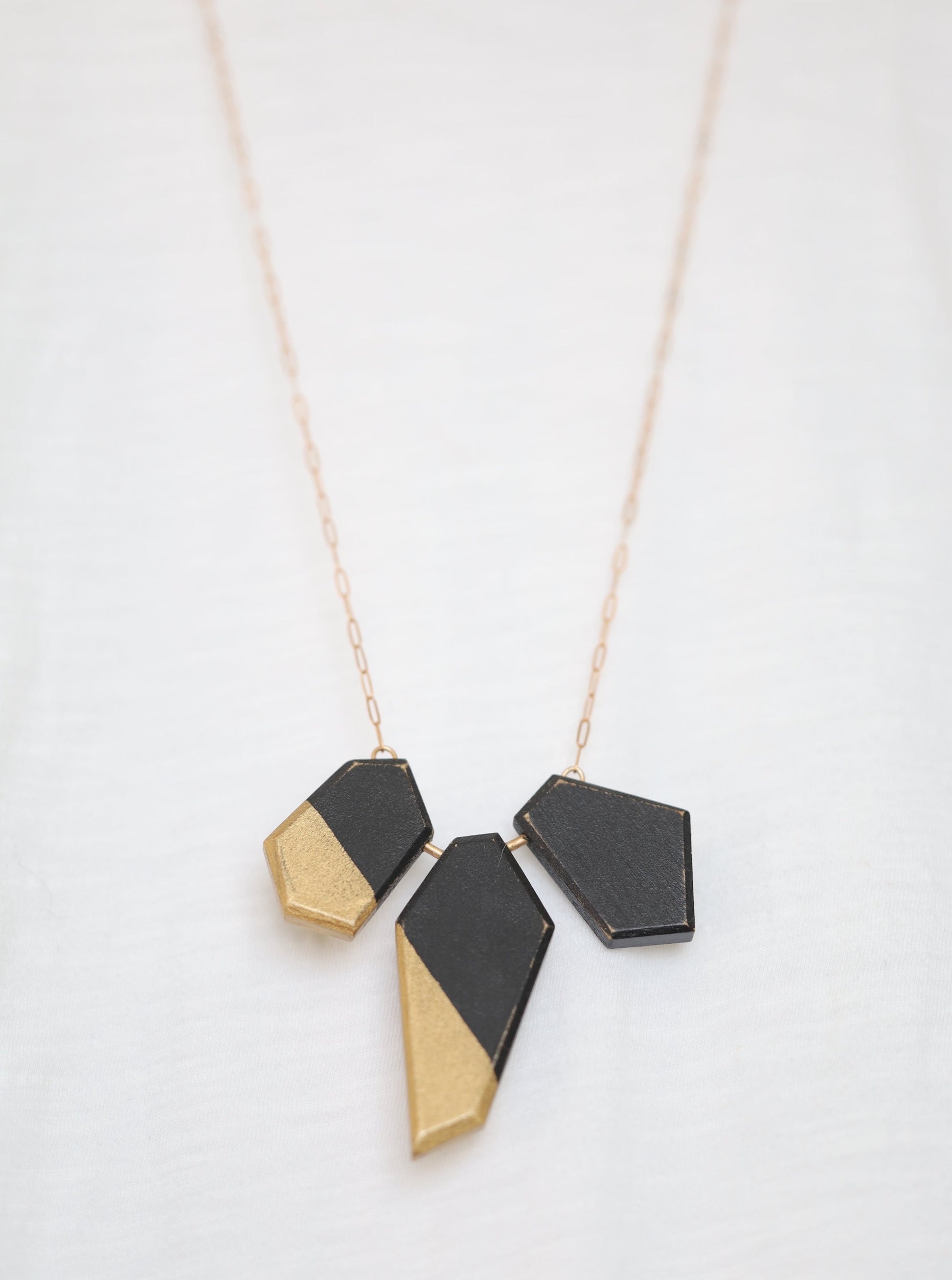 Wooden pieces painted black and gold on a bronze chain.