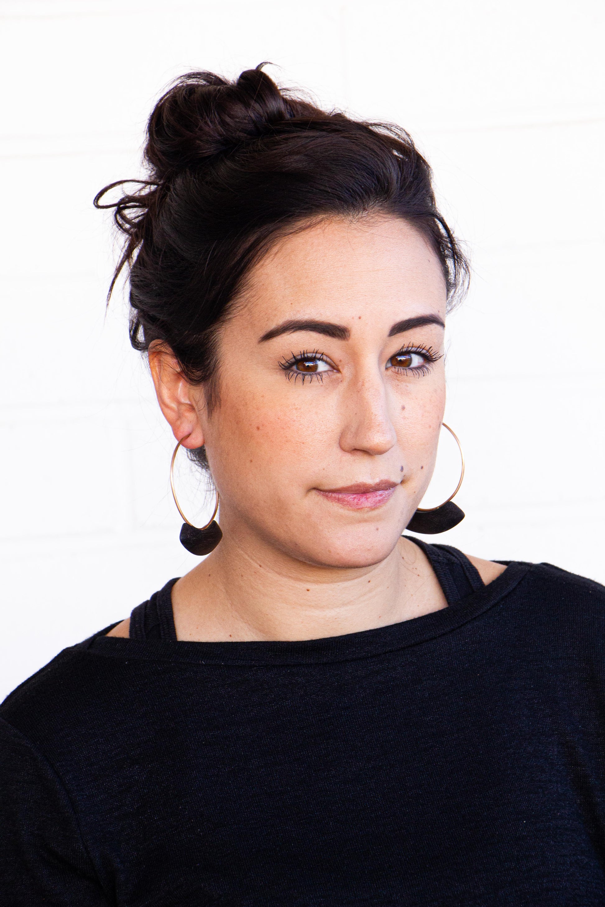 Woman wearing bronze and burnt wood hoop earrings.