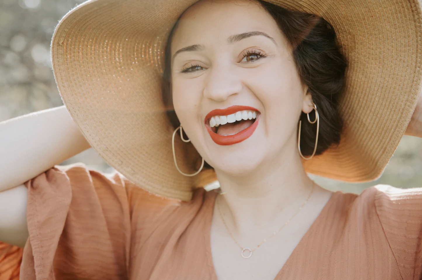Woman wearing large oblong gold hoops.