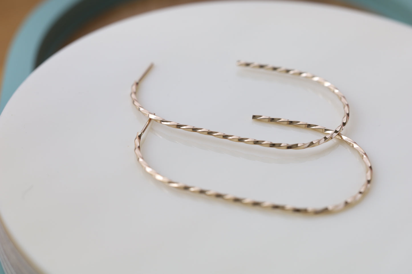 Pair of large twisted gold hoop earrings. Close up.