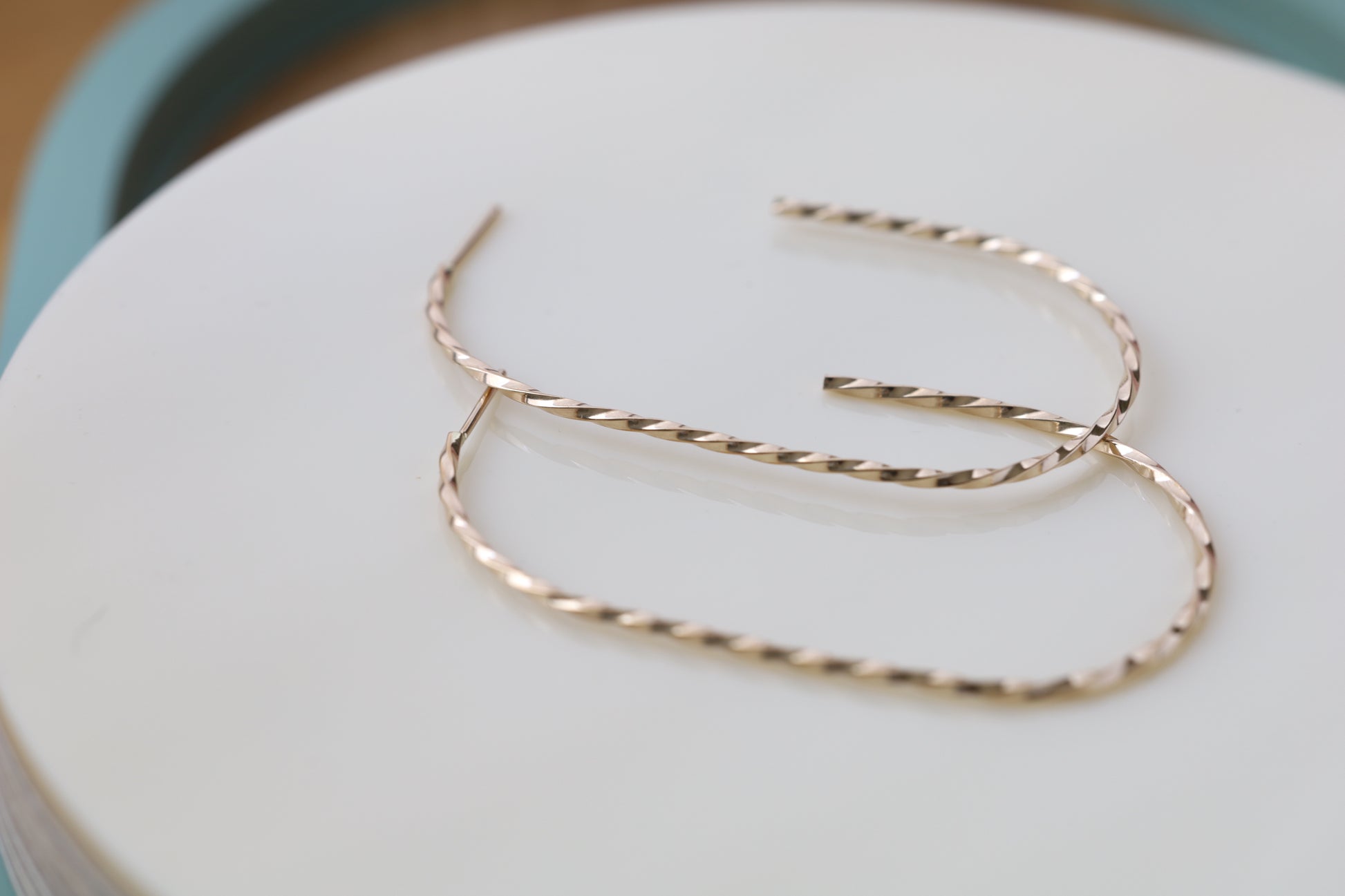 Pair of large twisted gold hoop earrings. Close up.