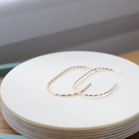 Pair of large twisted gold hoop earrings.