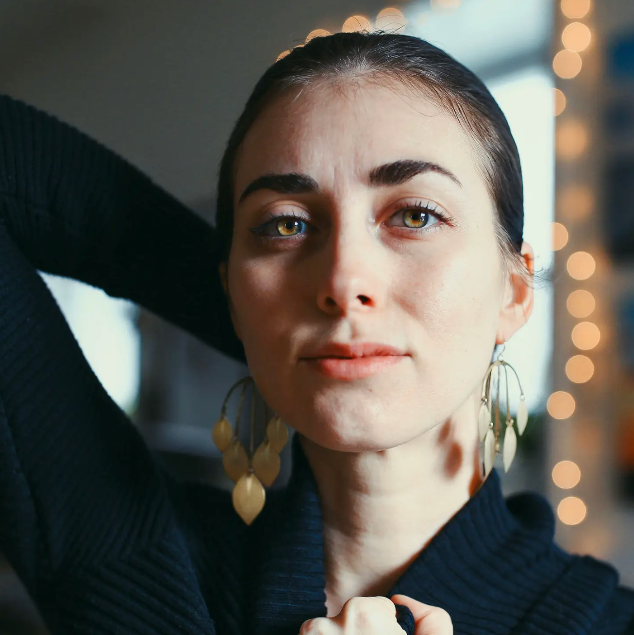 Woman wearing large gold statement earrings made from leaf shapes, front view.
