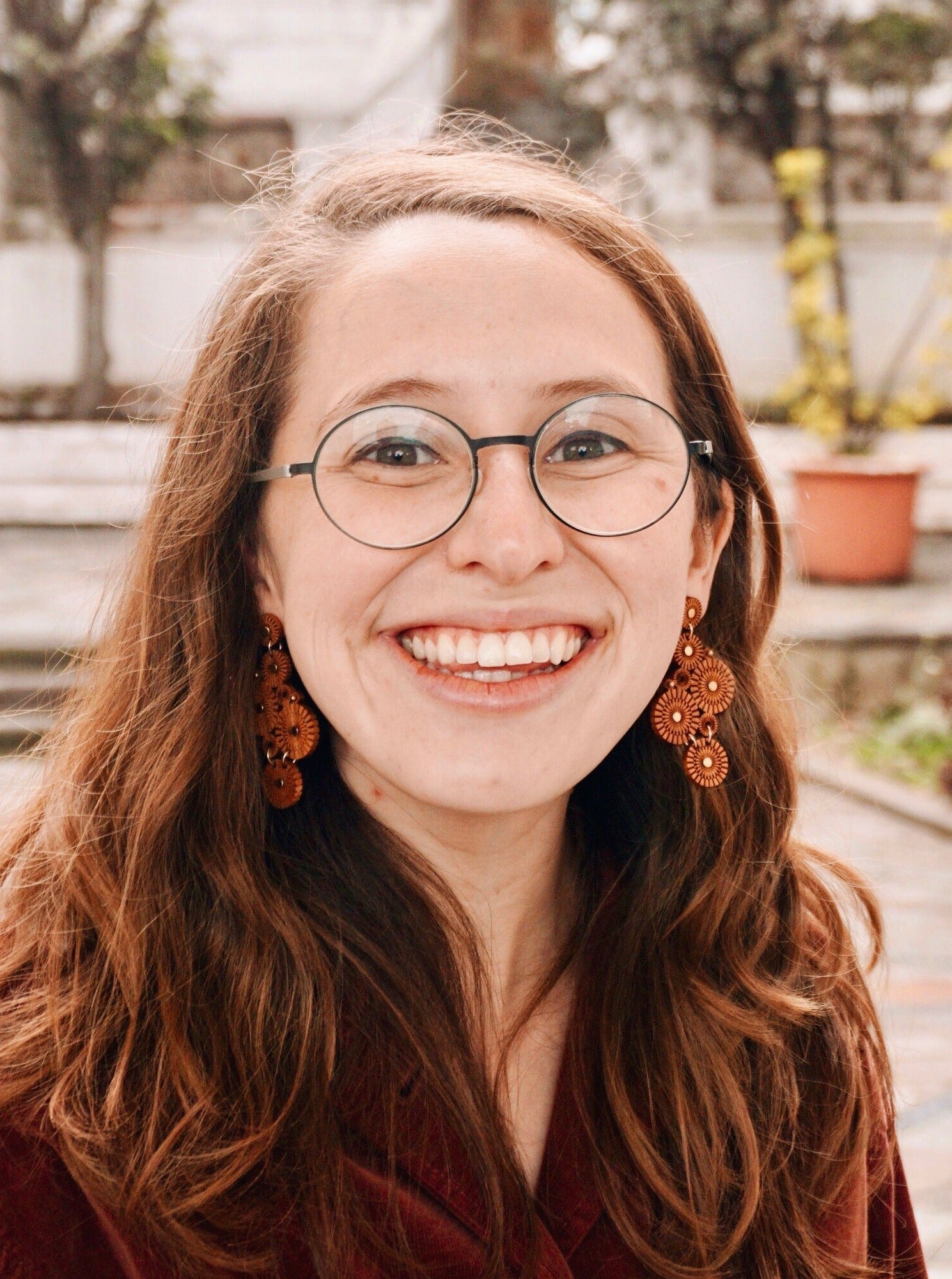 Woman wearing statement earrings made of various size laser carved circles, with brass accents.