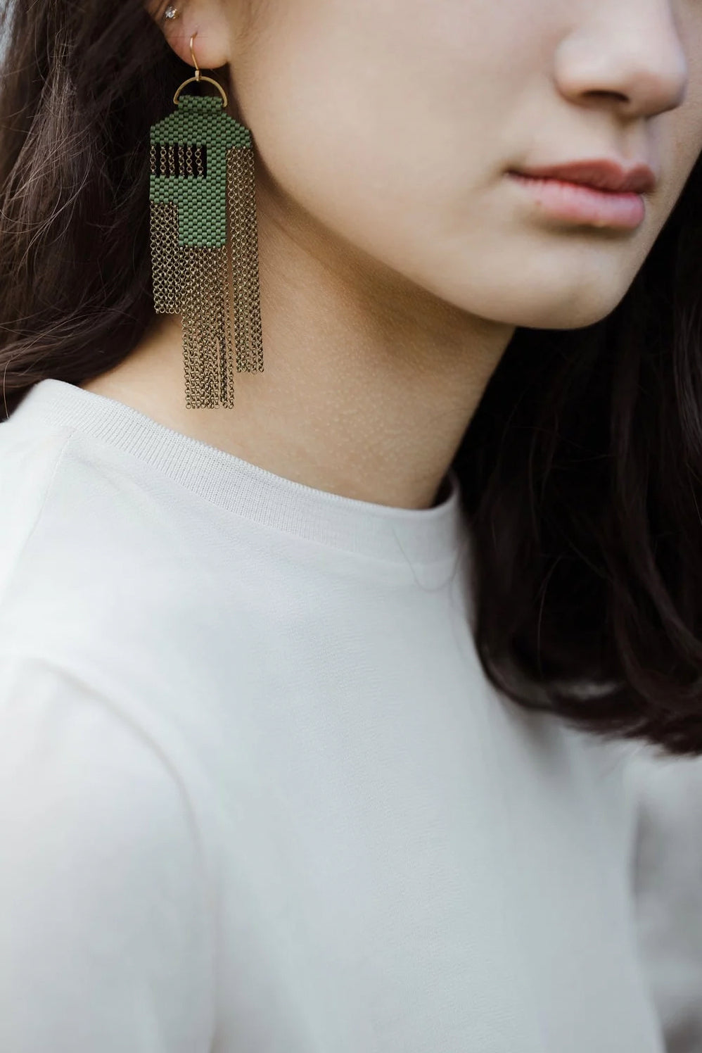 Woman wearing moss green beaded statement earring.