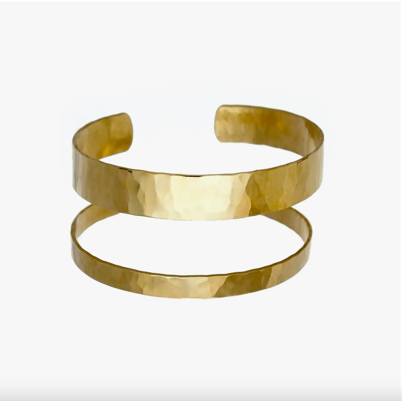 Woman wearing two sizes of hammered brass cuff bracelets, medium and wide.