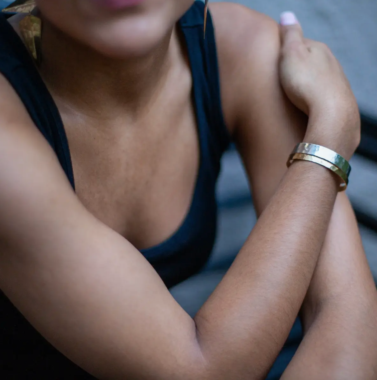 Woman wearing two sizes of hammered brass cuff bracelets.