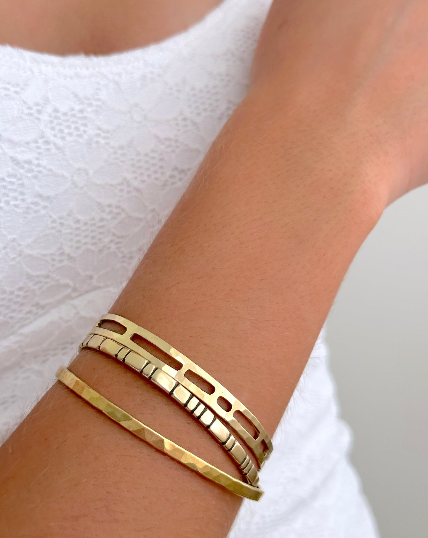 Woman wearing various styles of gold cuff bracelets.