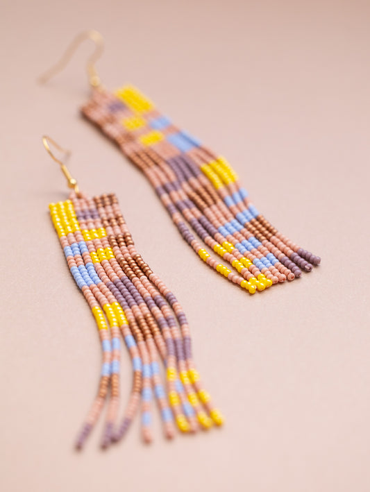 Long beaded earrings in yellow, light blue, copper, and pink.