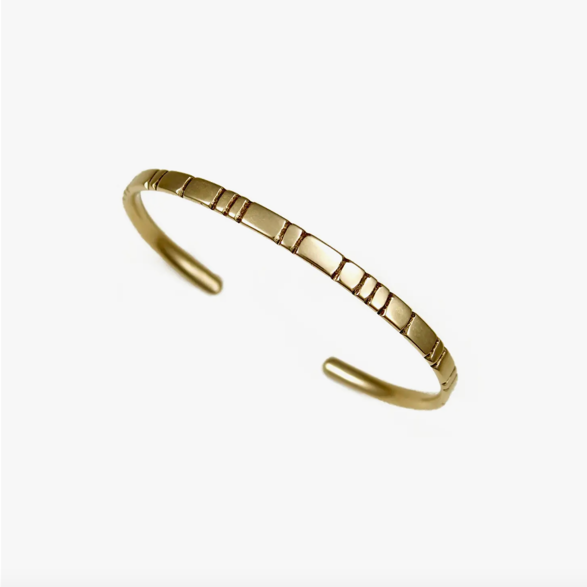 Gold cuff bracelet with linear carved designs.