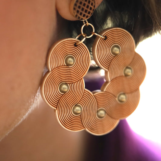 Close up of woman wearing laser carved wooden statement earrings.