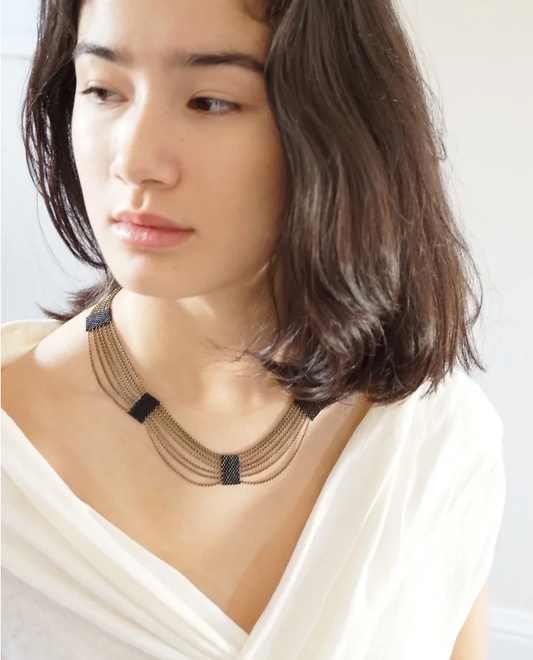 Woman wearing elegant draping necklace made of chain and black beads.