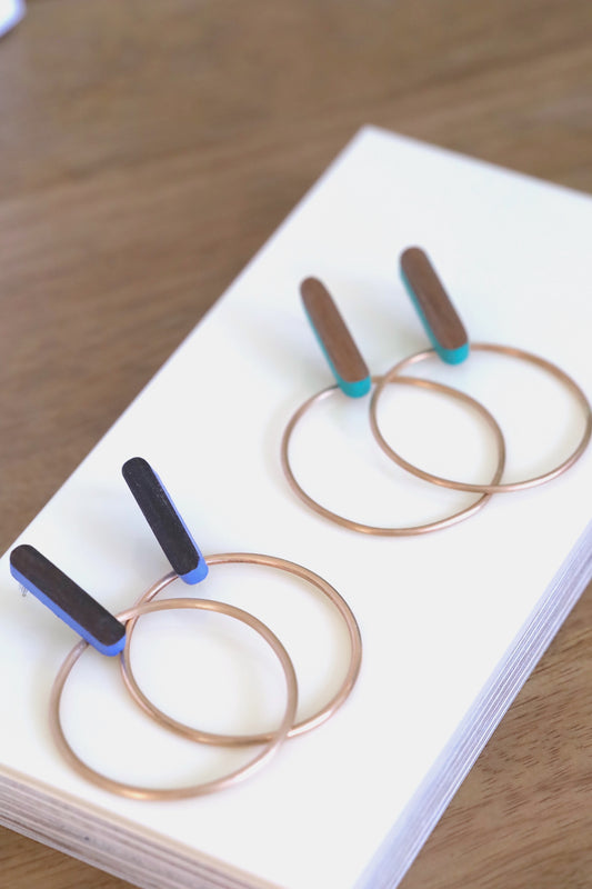 Two sets of earrings made of wood posts with bronze hoop earrings. Shown in blue and turquoise.