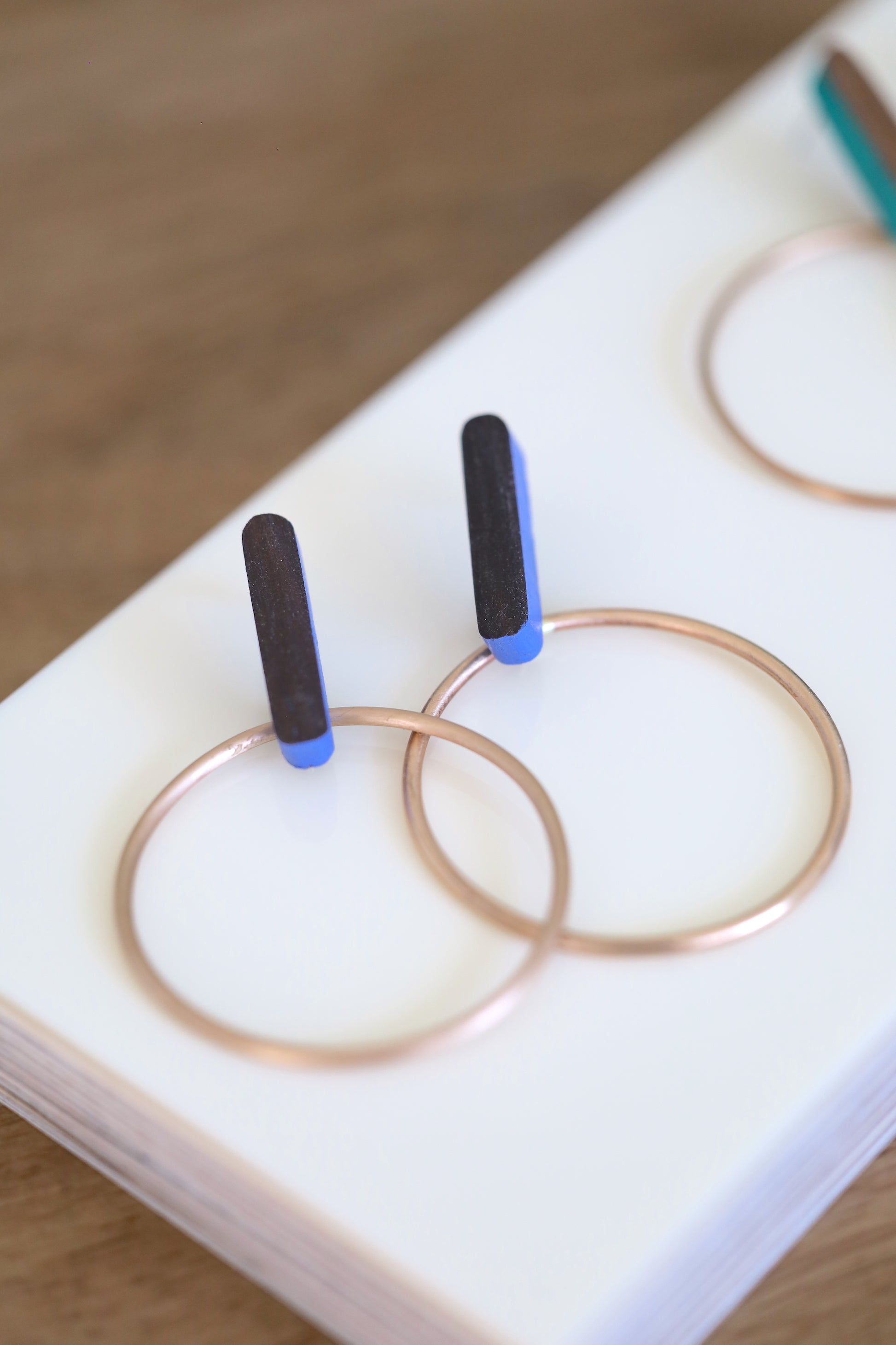 Earrings made of wood with blue painted accents and bronze hoops.