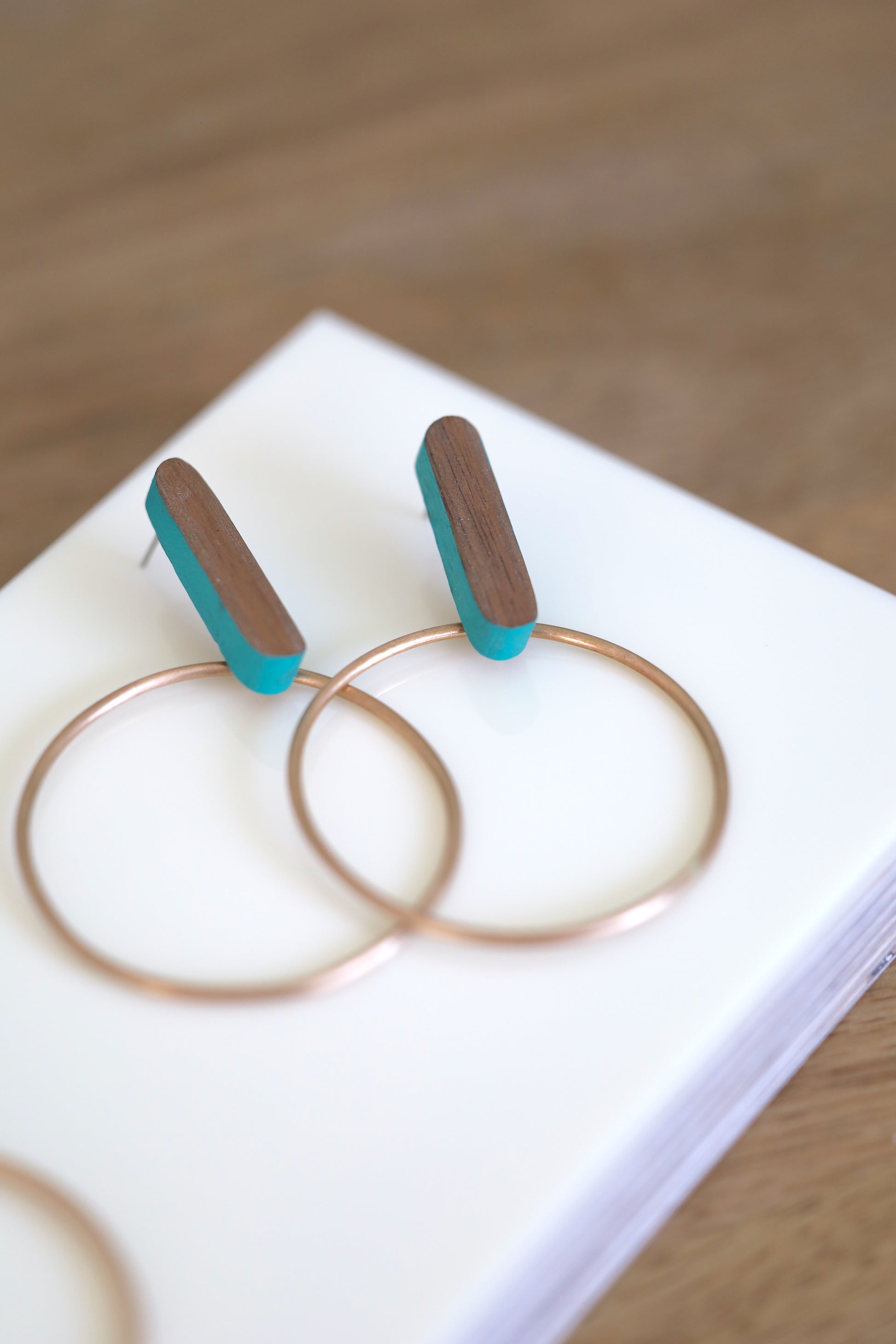 Earrings made of wood with turquoise painted accents and bronze hoops.