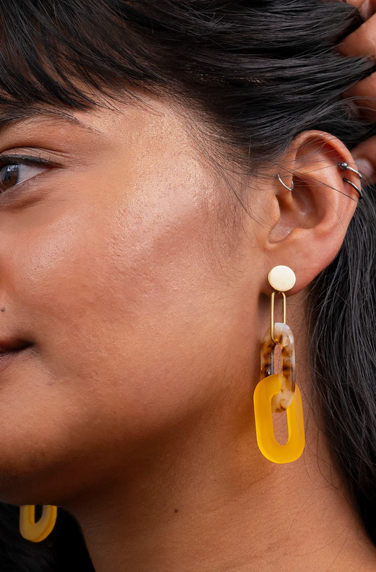 Woman wearing tortoise shell and citrus acrylic link earrings.