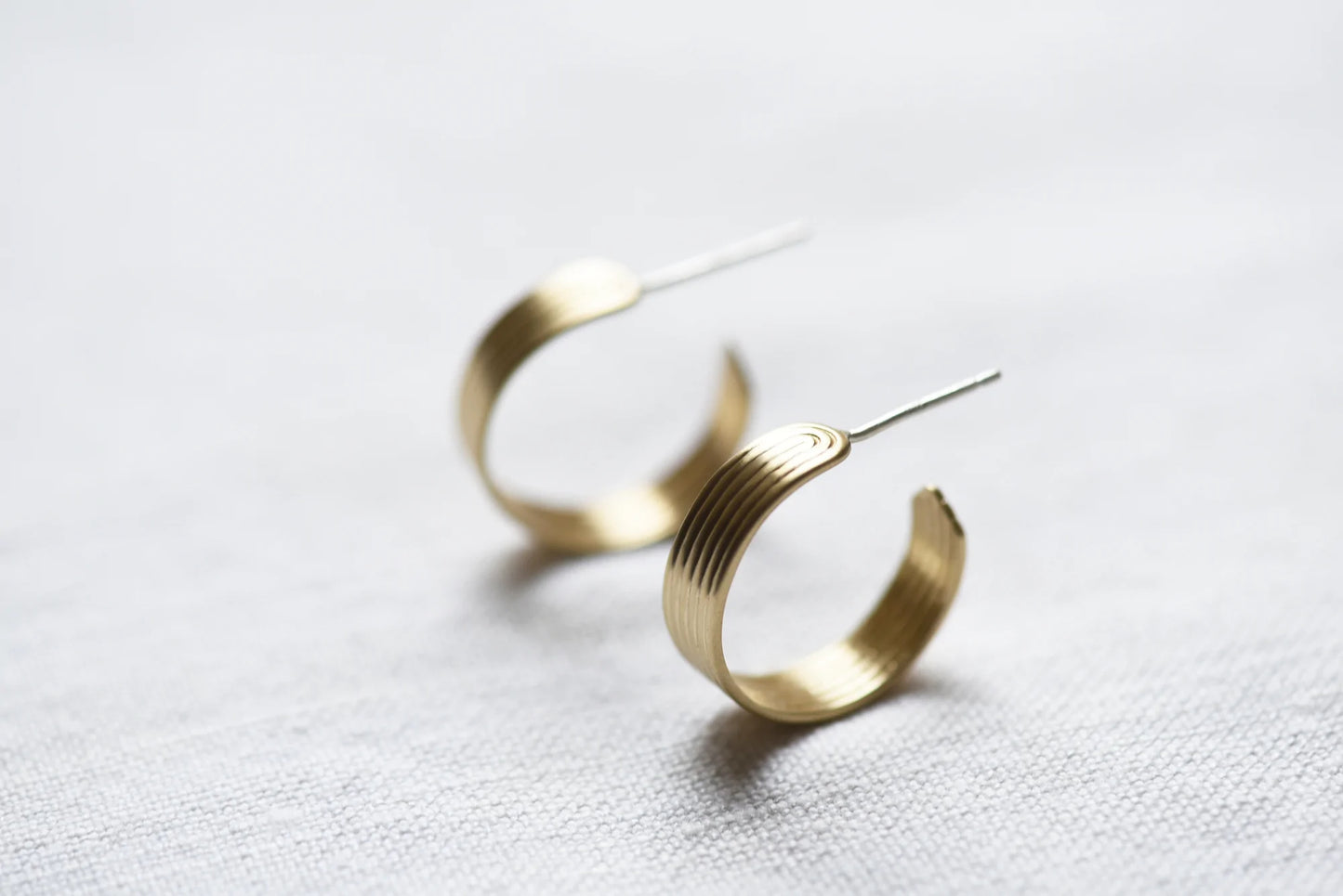 Gold hoop earrings with linear designs.