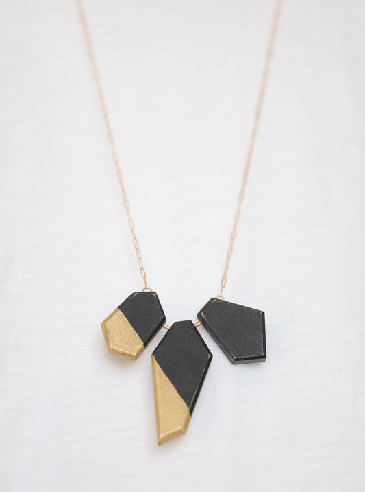 Wooden pieces painted black and gold on a bronze chain.