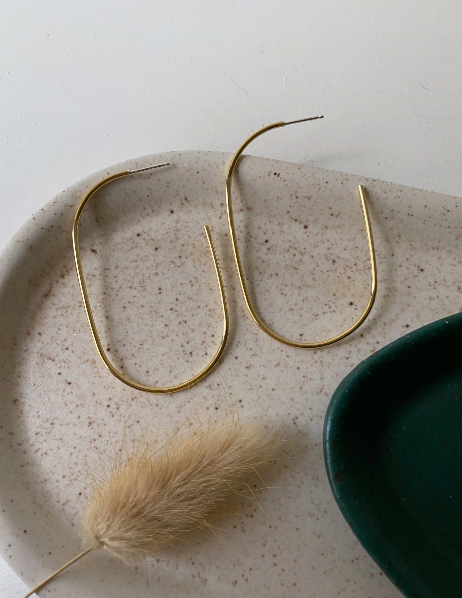 Large oblong gold hoops made from brass, propped up on side of dish.