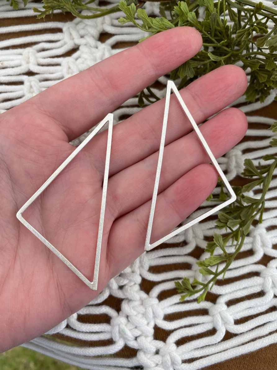 Hand with pair of large sterling silver triangle earrings