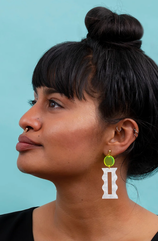 Woman wearing florescent yellow and white modern earrings