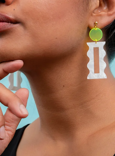 Close up of woman wearing florescent yellow and white modern earrings